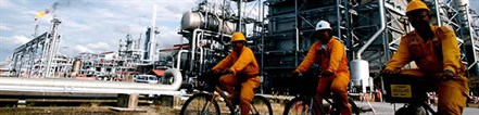 Petronas Mlng Workers Riding Bikes Near Lng Plant